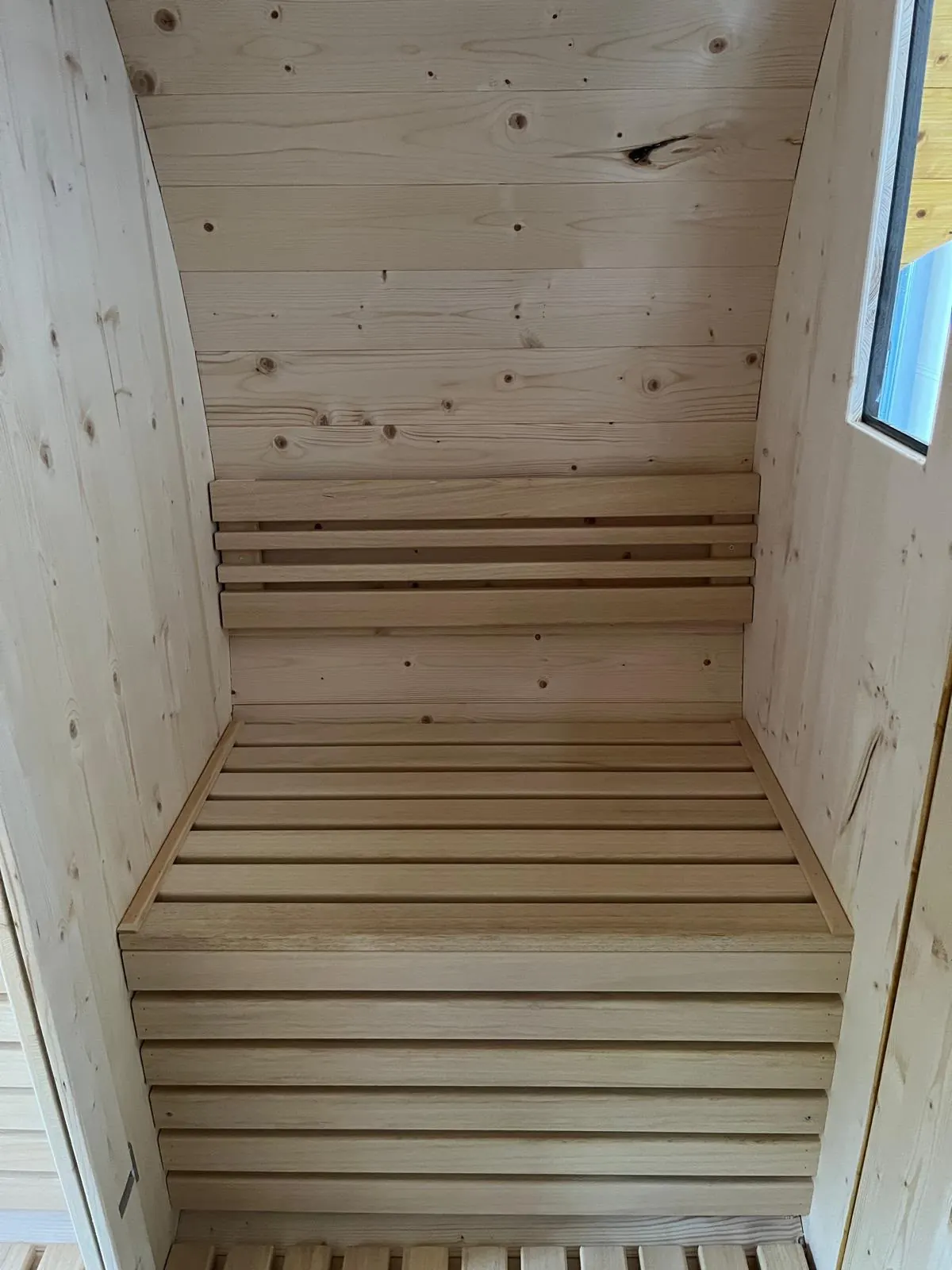 Heller Innenraum der Fasssauna mit Holzliegen